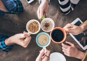 Overhead view of people holding coffee cups together on a table